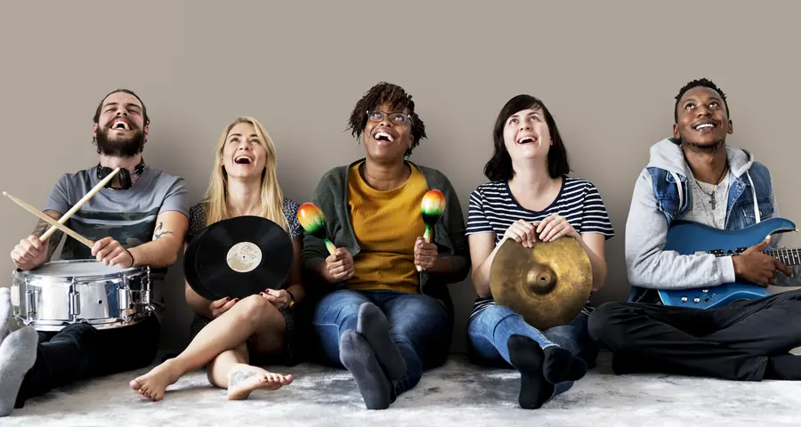 Un gruppo di persone sedute con strumenti musicali e un vinile