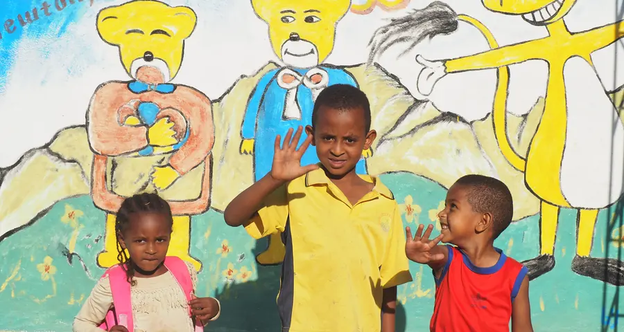 Bambini sorridenti davanti a un murale colorato in una scuola dell'infanzia in Etiopia